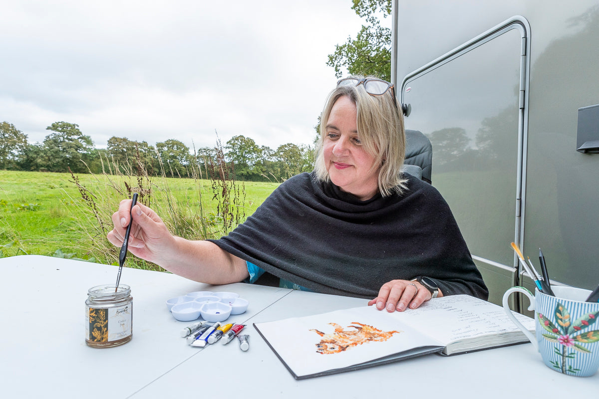 Photo of artist Jo Scott painting outside in nature