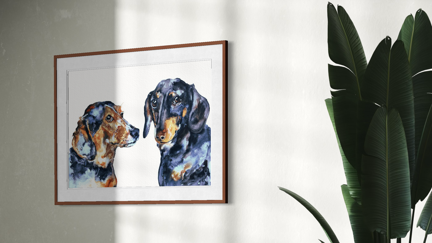 A framed watercolor painting of two dachshunds hanging on a light gray wall, with a green houseplant visible on the right side of the frame.