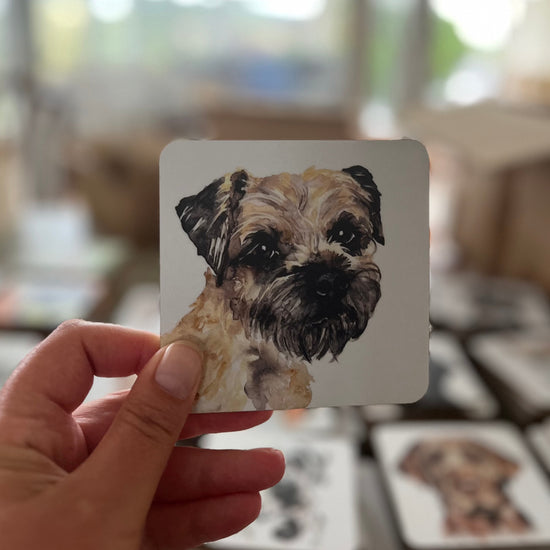 A Border Terrier painting on a coaster