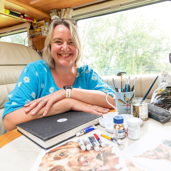 Artist Jo Scottsitting at a table with art supplies in her motorhome