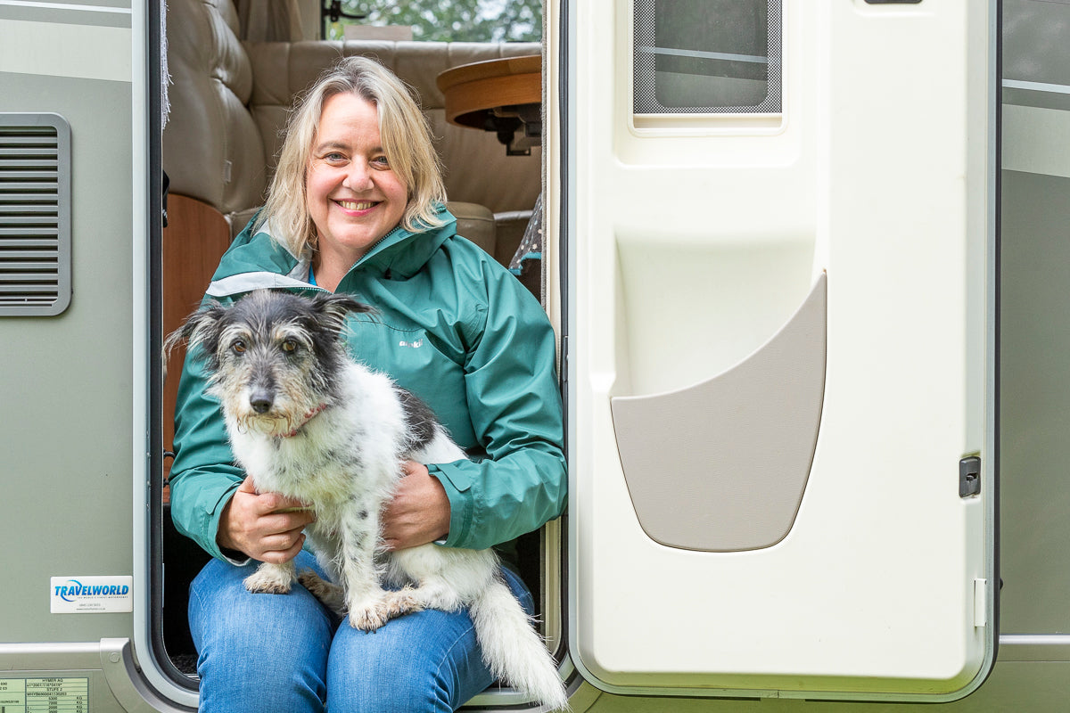 Photo of artist Jo Scott and her dog Thomasina sat in the doorway of her motorhome